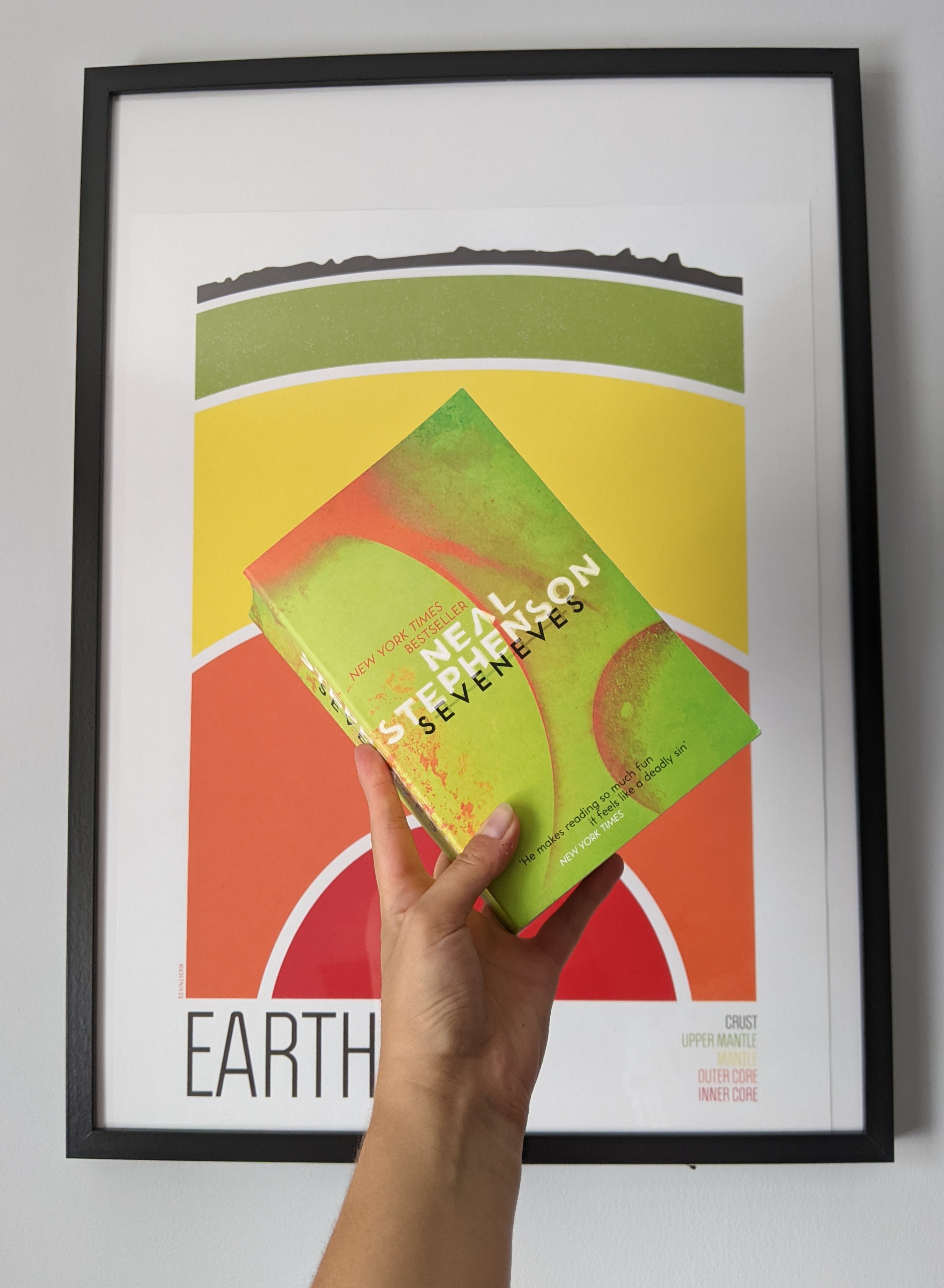 A picture of a copy of Seveneves against a backdrop of a painting of Earth's layers