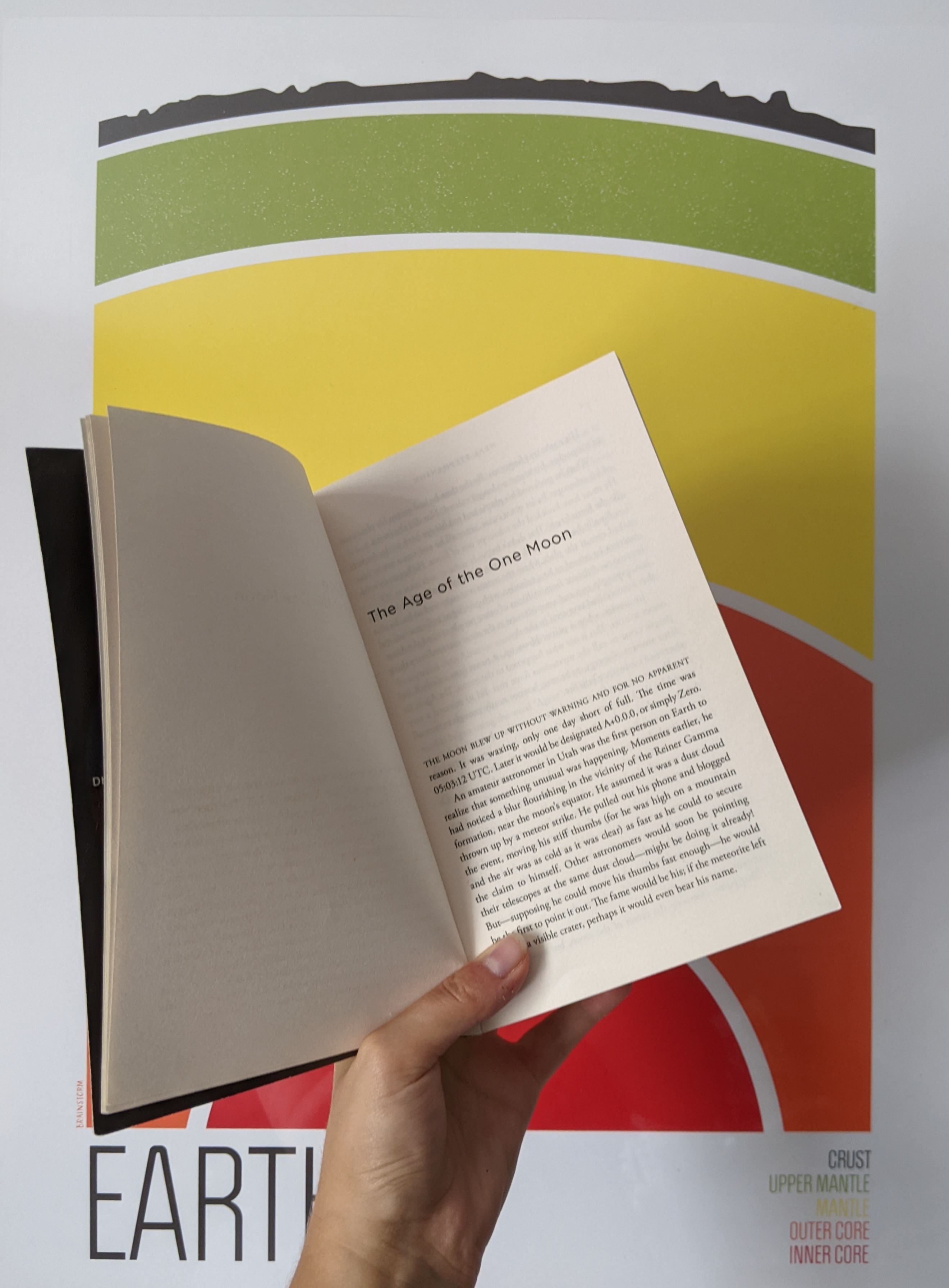 A picture of a copy of Seveneves against a backdrop of a painting of Earth's layers